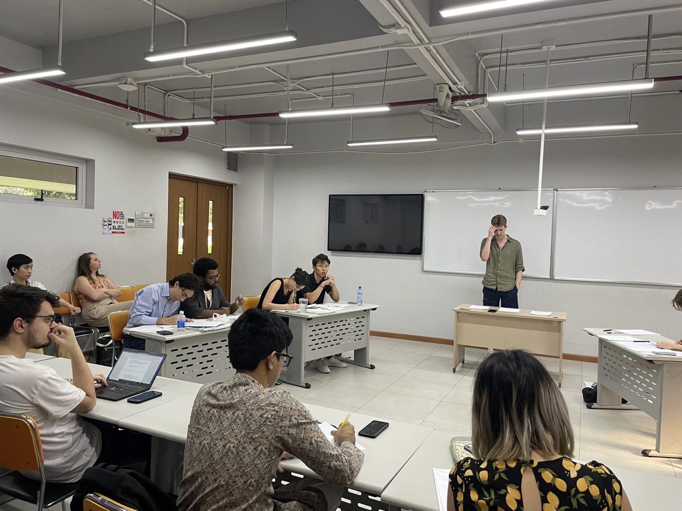 A debater on their feet mid-speech while both benches and the judges follow the argument.