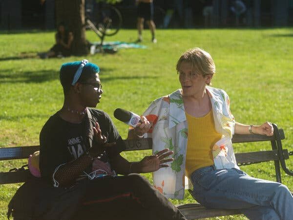 Two people on a park bench, one holding a microphone while the other answers